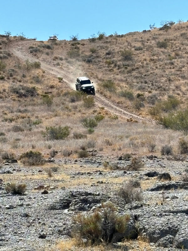 4x4 vehicle descending a dirt hill during the Weekend Offroad Driving Workshop while practicing controlled off-road hill descent techniques in a desert environment.