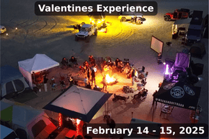 A nighttime aerial photo of the Weekend Offroad Valentines Experience event, showing overlanding rigs, tents, lighting, and a group of attendees gathered around a large campfire in the desert on February 14–15, 2025.
