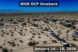 A large aerial shot of the WOR DCP Giveback 2026 showing over 100 off-road vehicles and camp setups spread across the open desert landscape in Southern California. The scene includes tents, rooftop campers, recovery rigs, and a long line of SUVs and trucks arriving for the community volunteer and overlanding weekend event held January 16–18, 2026.