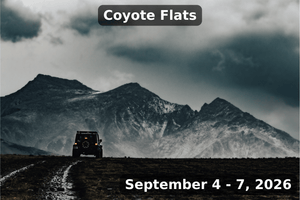 A lone off-road vehicle drives along a muddy trail toward dramatic dark mountains under stormy skies. The image includes labeled text at the top reading “Coyote Flats” and at the bottom “September 4 - 7, 2026.”