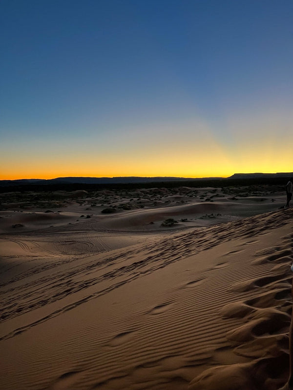 Sunset over desert sand dunes during the Lake and Canyon Relaxation 2026 trip.