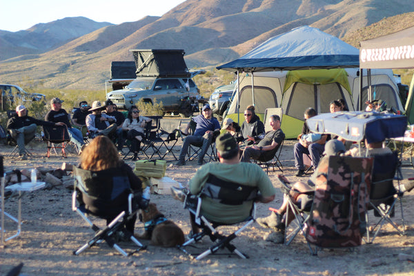 Weekend Offroad campers gathered around a campfire during an overlanding adventure in the desert.