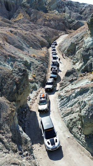 A convoy of off-road and overland vehicles driving through a narrow desert canyon during a Weekend Offroad expedition.