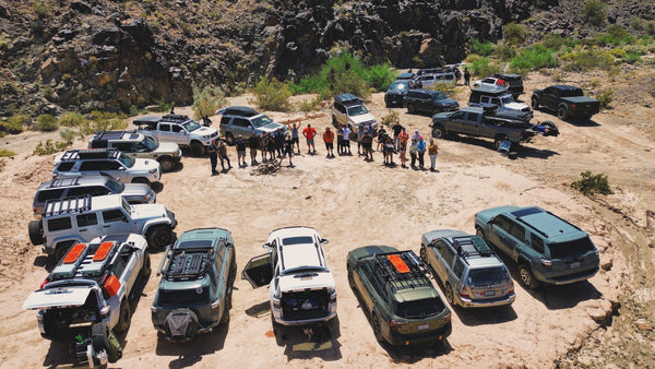 A group of off-road vehicles parked in a circle in the desert with participants standing together at a Weekend Offroad event.