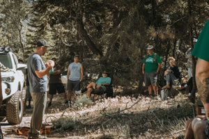 Instructor teaching an off-road recovery class in the forest while participants listen during a Weekend Offroad event.