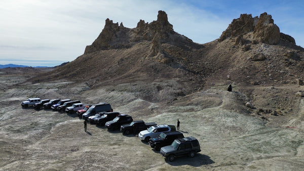 Line of overland vehicles parked in front of desert rock formations during a Weekend Offroad expedition adventure.